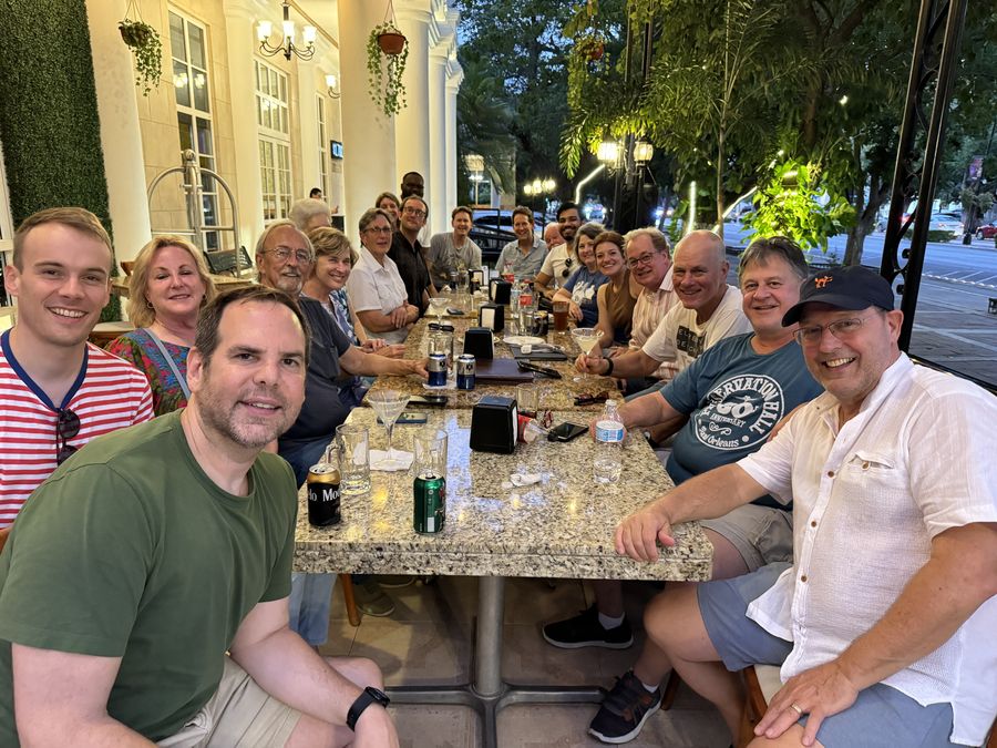 Attendees at a long outdoor dinner table in the evening