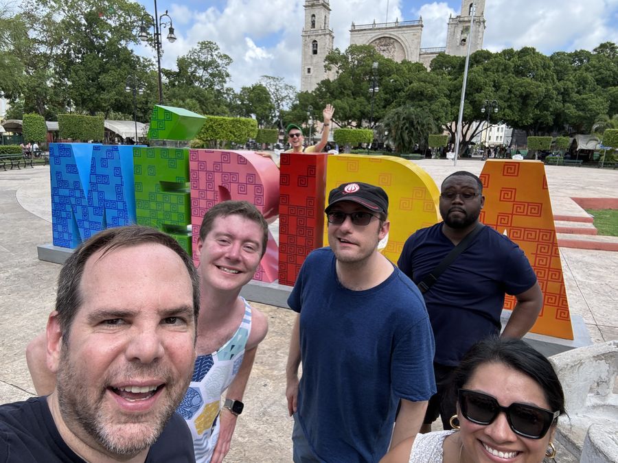A group posing at brightly painted city letters in a plaza
