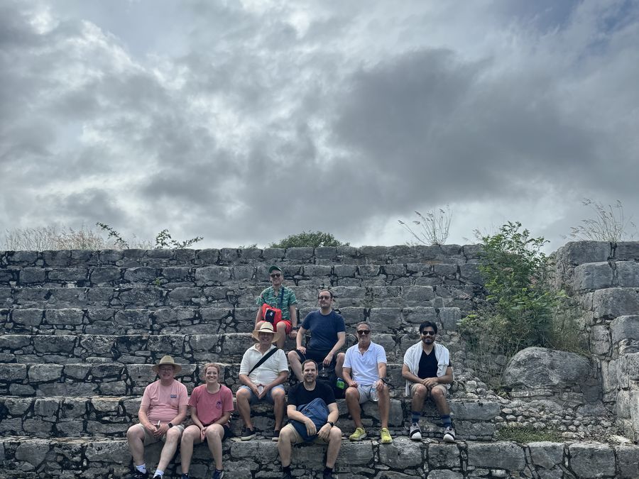 Attendees seated on the stone steps of a Mayan ruin