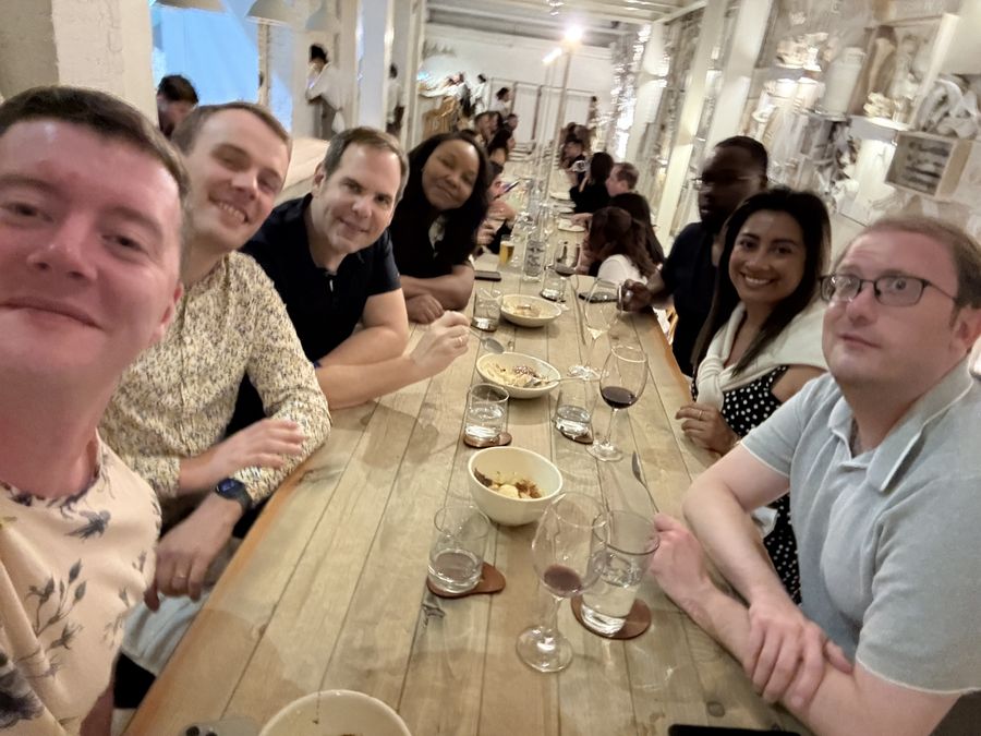 Attendees along a wooden dining table at dinner