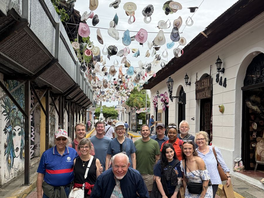 The group on a street canopied with hundreds of hanging hats
